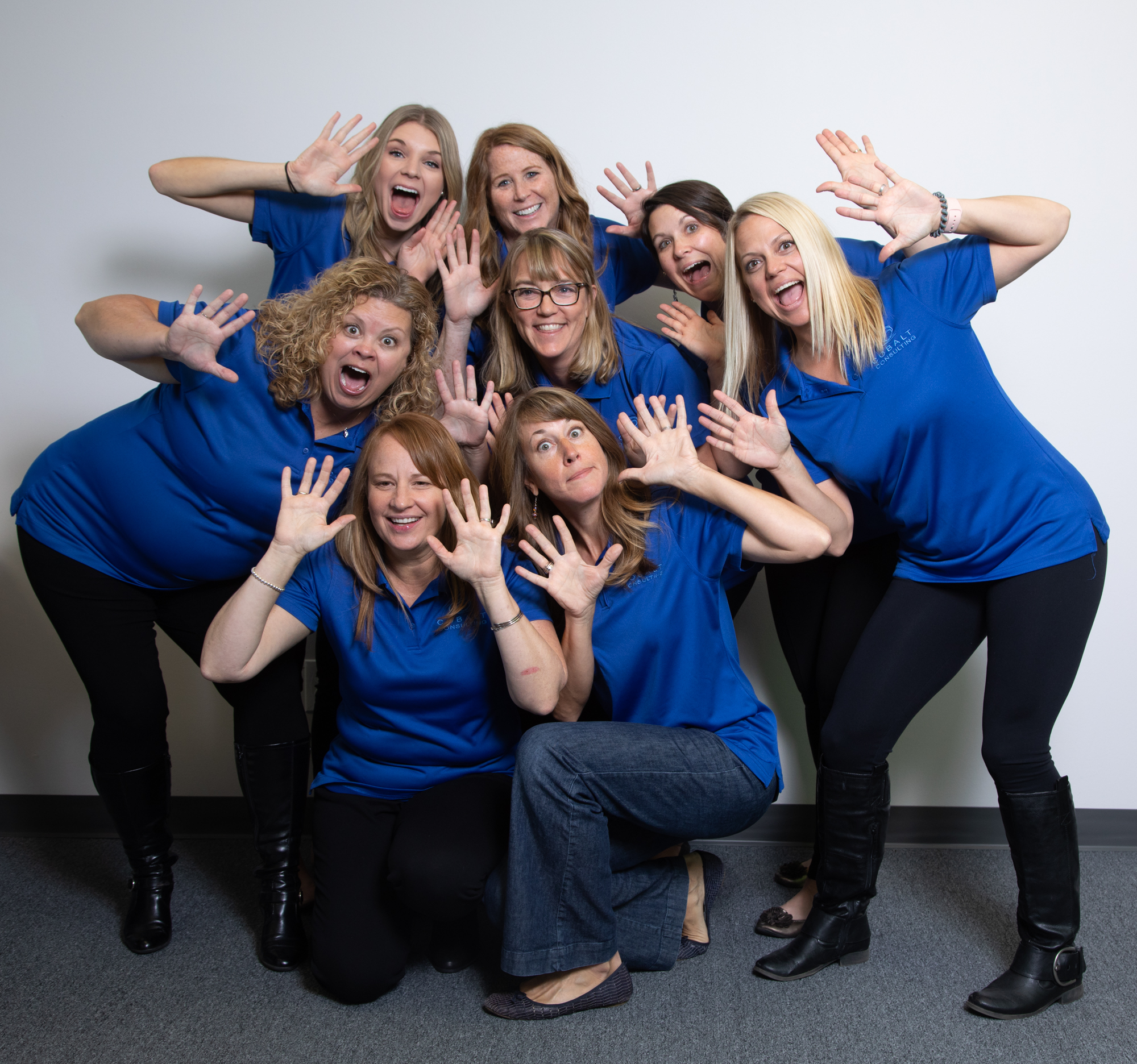 The team from Cobalt Consulting poses playfully for a fun group photo. Wearing matching blue polo shirts, the group showcases their vibrant and energetic team spirit.